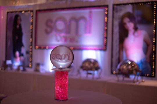 Beautiful LED Logo Topper with Pink Chips Centerpiece and Custom Backdrop with Blow Up Pictures for Custom Lounge Set Up