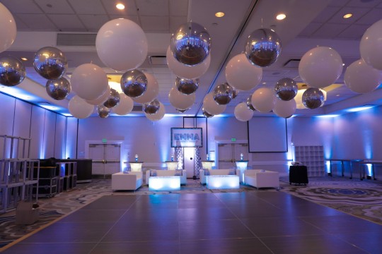 Classic Large White Balloons and Metallic Silver Orbz Around Dance Floor Ceiling, Custom Lounge Set Up with Pillows and Custom Printed Backdrop with Balloon Columns for Party Decor