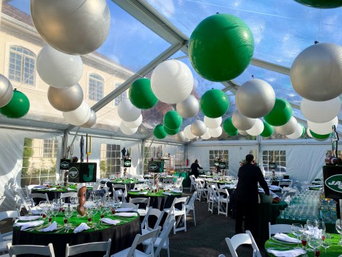 Amazing Jets Inspired Ceiling Treatment with Large Green, White and Silver Balloons, Turf Table Toppers and Football Centerpiece with Custom Logo Cube and Cut Outs for Tent Party Decor
