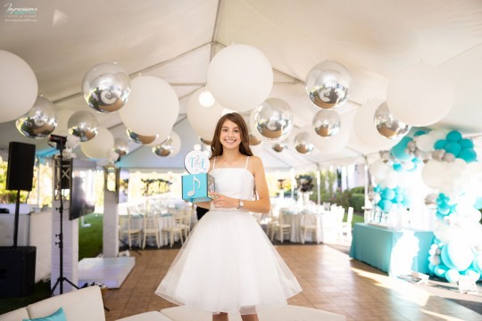 Tent Ceiling Treatment with Large White Balloons & Metallic Silver Orbz, Beautiful White and Turquoise Organic Balloon Wall and Bat Mitzvah Girl Holding her Custom Logo & Picture Cube for Cocktail Centerpiece