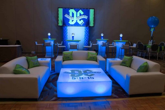 Custom Lounge Setup with Couches, LED Tables with Logo Decals, LED Hightops with Centerpieces & Logo Backdrop for Music Themed Bar Mitzvah at the Doubletree Tarrytown