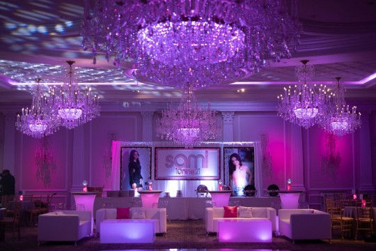 Beautiful Custom LED Lounge Setup with Pink Uplighting Around Room, Couches with Logo Pillows, Logo Coffee Tables, High Top and Custom LED Backdrop with Blowup Pictures for Bat Mitzvah Decor