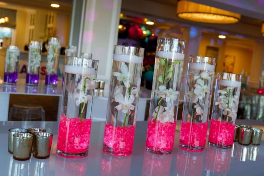 Orchid Centerpiece Floating Candles Cylinders with Hot Pink chips on Airport Table