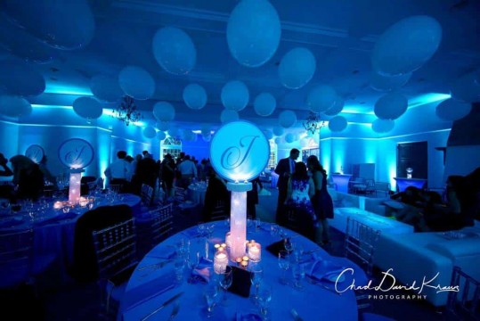Beautiful Bat Mitzvah Setup with LED Logo Centerpieces, White Ceiling Balloons & Turquoise Uplighting at Temple Shaaray Tefila, Bedford